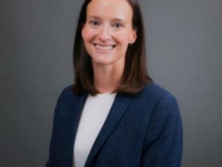a woman wearing a blue blazer and white shirt smiles