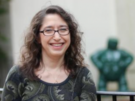 Woman with brown hair and glasses smiles