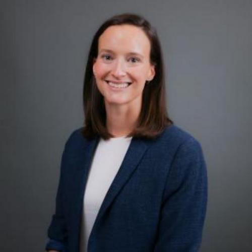 a woman wearing a blue blazer and white shirt smiles