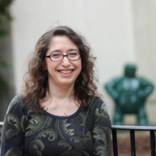 Woman with brown hair and glasses smiles