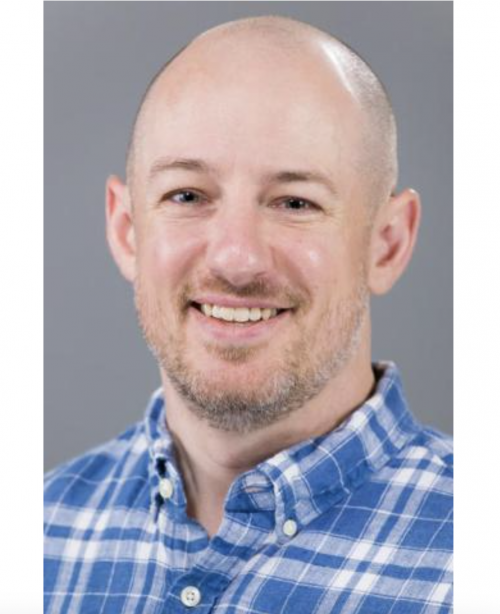Eric Hoover in a blue collared shirt with a grey background